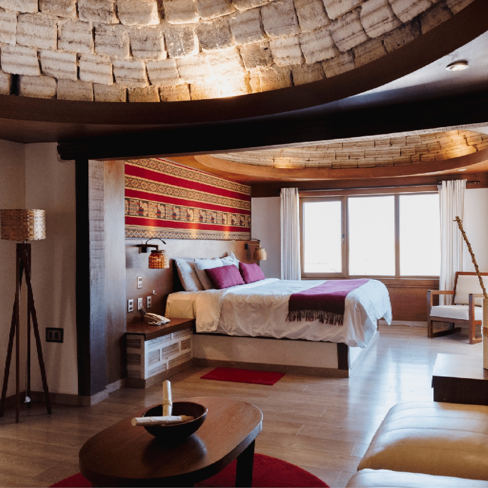 Spacious bedroom at Palacio de Sal with salt-block ceiling, large bed, sitting area, and wide windows.