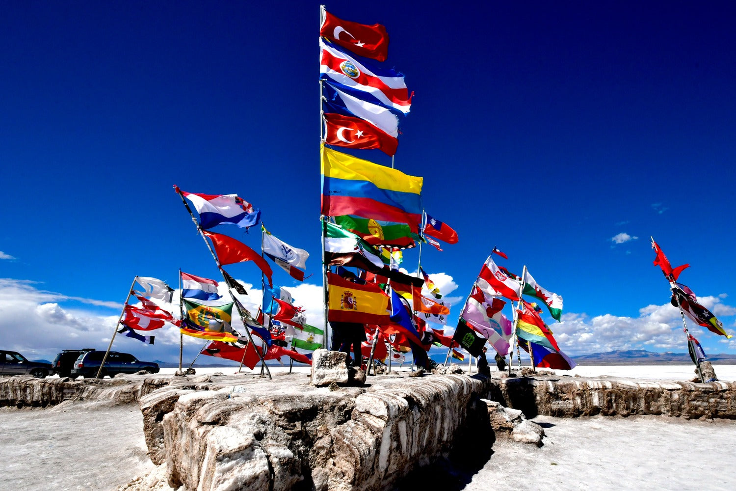 International flags monument on the Uyuni Salt Flat under a deep blue sky, Bolivia