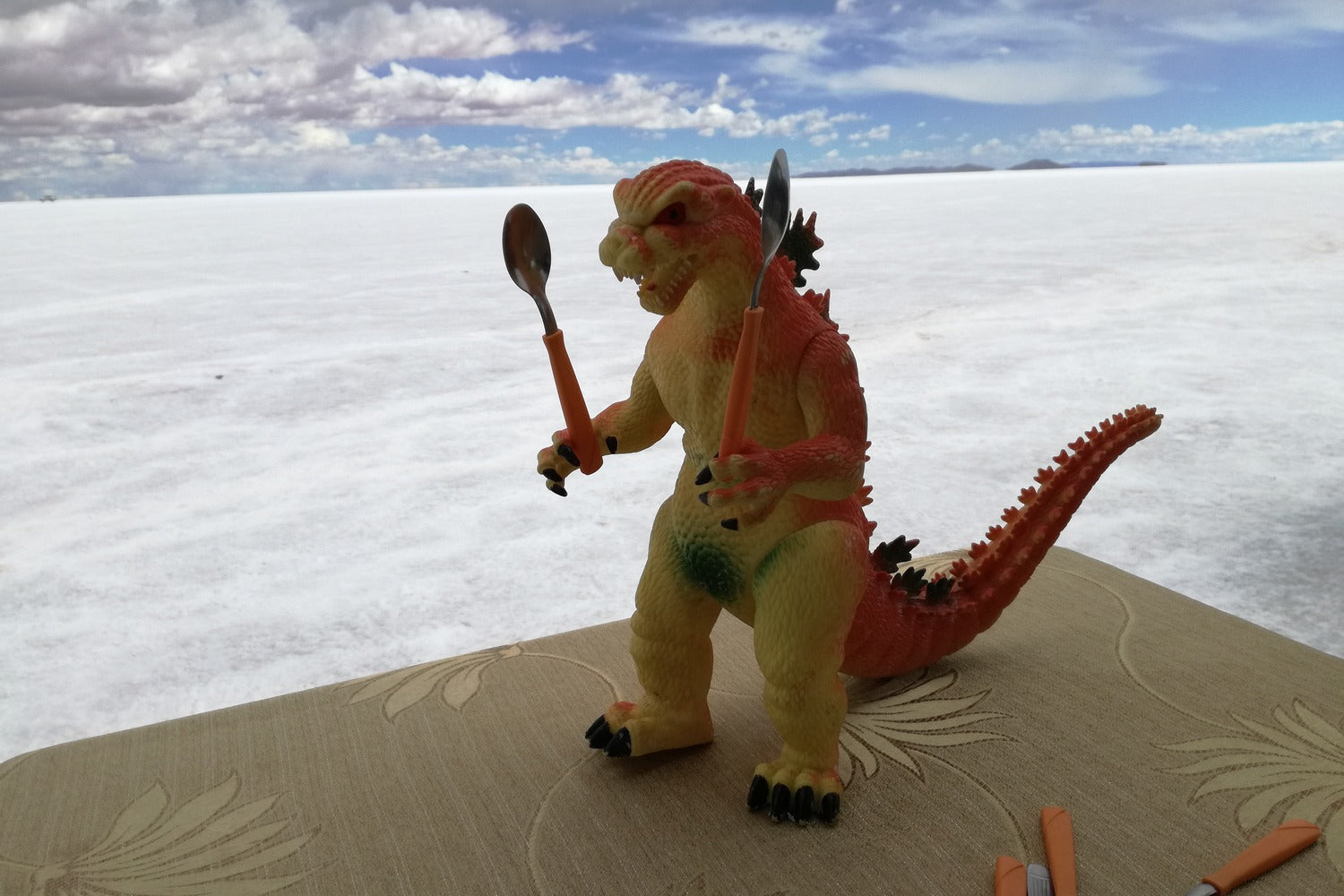 Toy dinosaur with a spear on a salt flat landscape