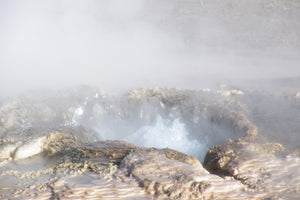 Foamy waves crashing against rocks with a hazy background