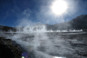 Geothermal area with steam rising from hot springs against a blue sky