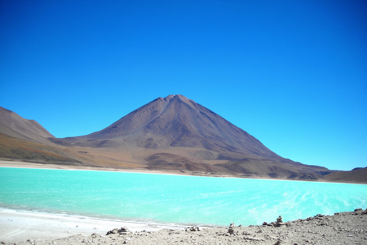 Laguna Verde with turquoise water below Licancabur Volcano under a clear blue sky.