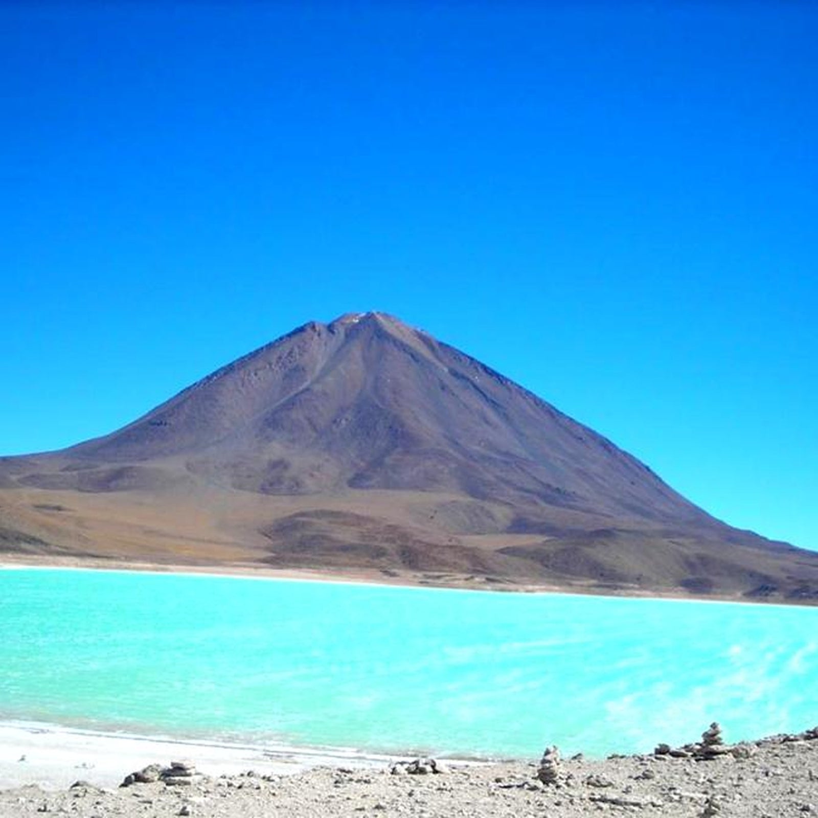 Laguna verde with Turquoise and Llicancabur in the background under a clear blue sky