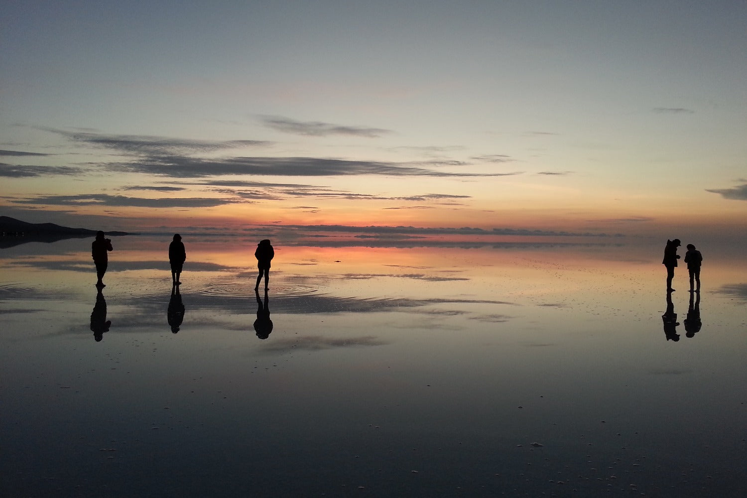 People enjoying last minute sunset moment at Uyuni salt falt with water.