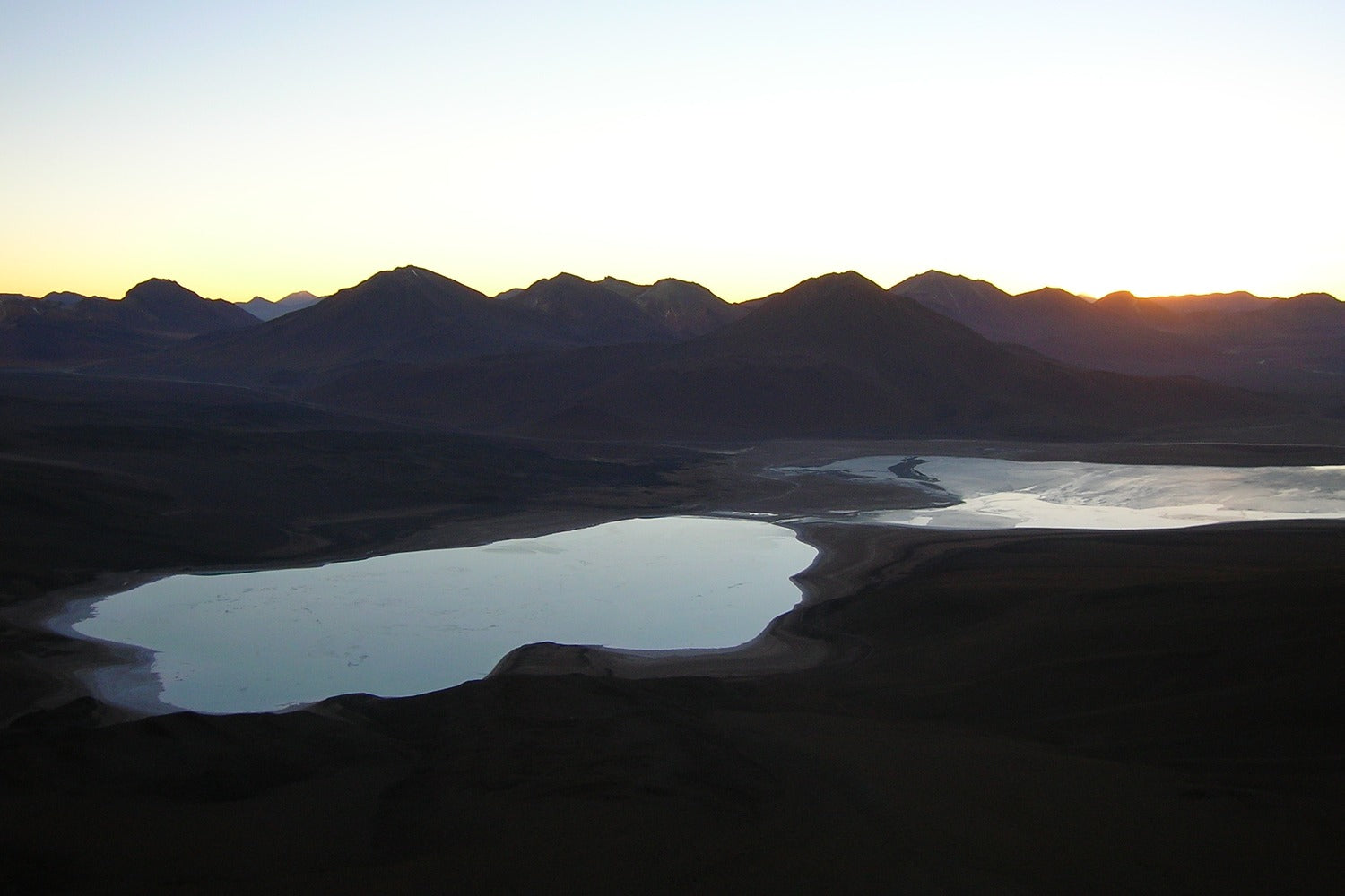 Lake surrounded by mountains at sunset.