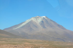 Mountain peak with snow cap under a clear blue sky.