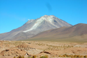 Desert landscape at South Lipez with Ollague Volcano under a clear blue sky
