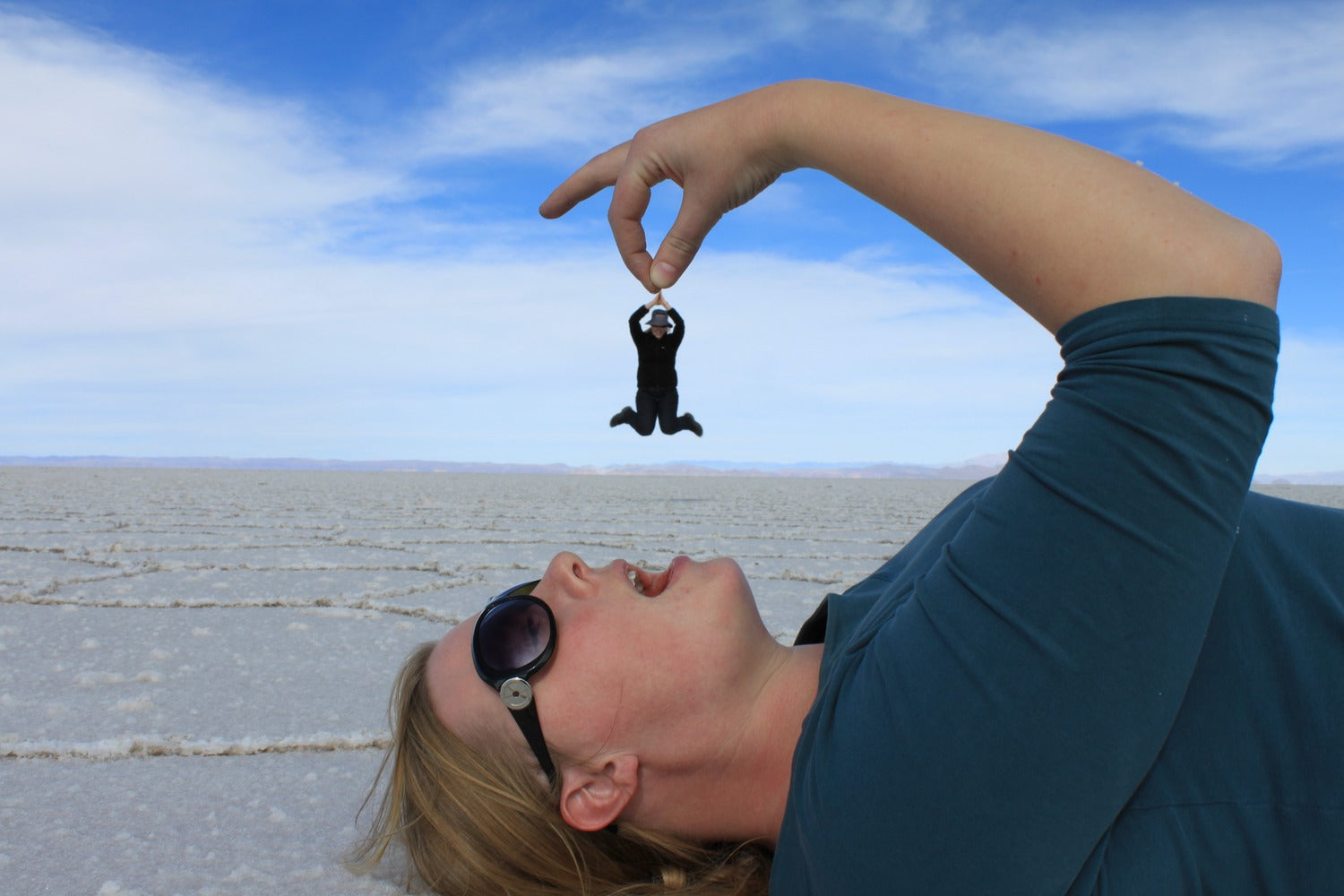 Person  lying on the salt flat at Uyuni salt flat with optic effect of holding someone above.
