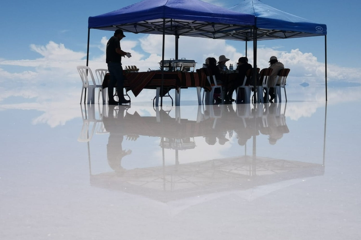 Exclusive lunch served in the middle of the spectacular mirror effect of the Uyuni Salt Flats.