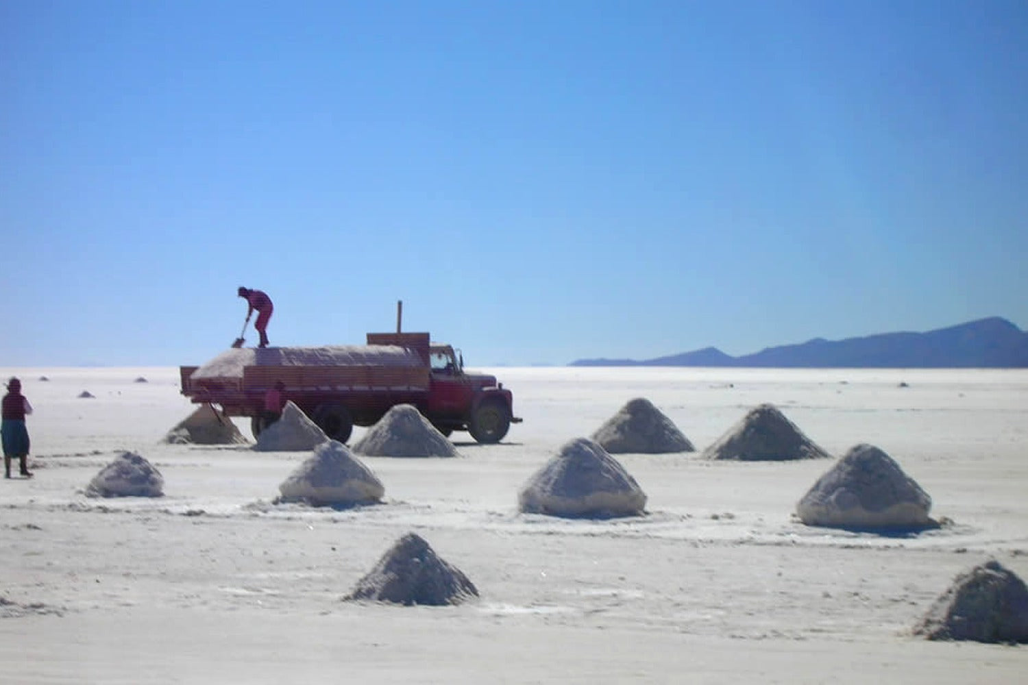 Local workers harvesting salt in the Uyuni Salt Flats using traditional artisanal extraction techniques.