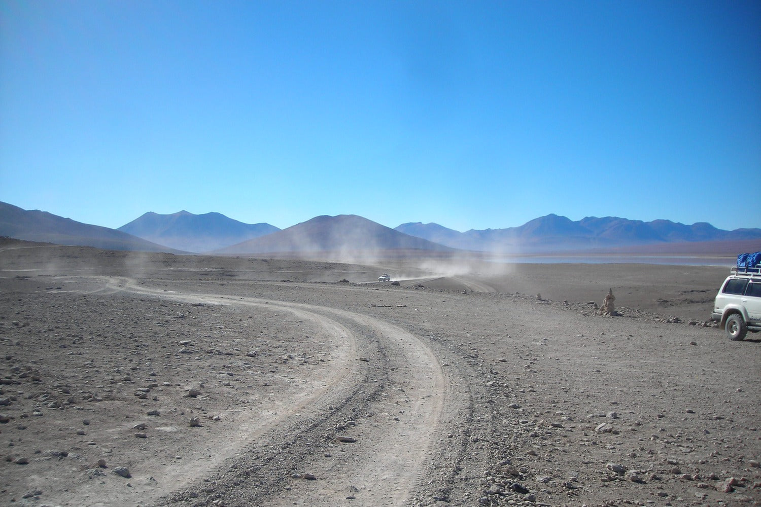 South Lipez desert landscape with a winding dirt road and mountains in the background.
