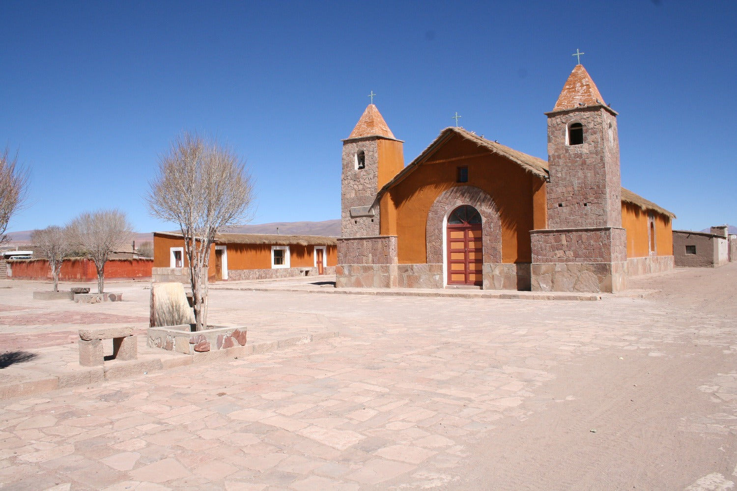 Small church with orange walls and a blue sky in the background.