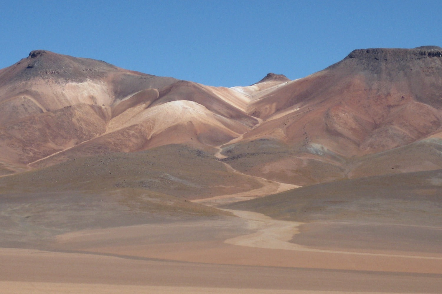 Desert landscape with colorful hills under a clear blue sky