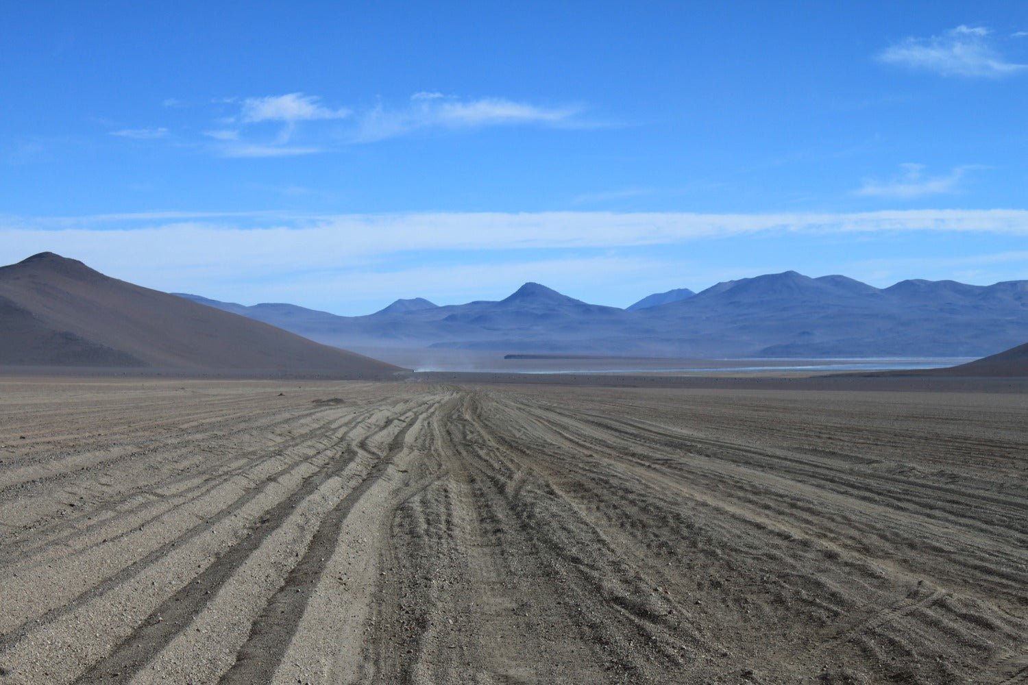 Desert landscape with mountains in the distance under a blue sky at South Lipez