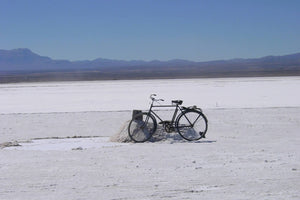 Vintage bicycle on a salt flat with mountains in the background