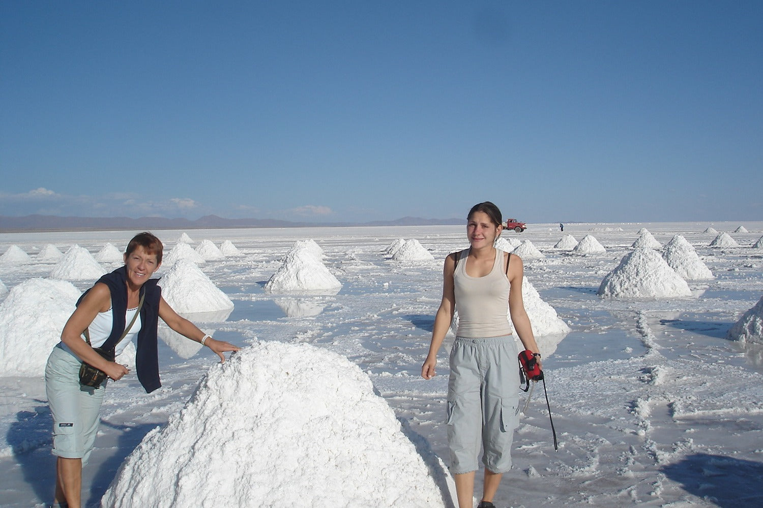 Two people exploring a salt flat landscape with large salt formations.