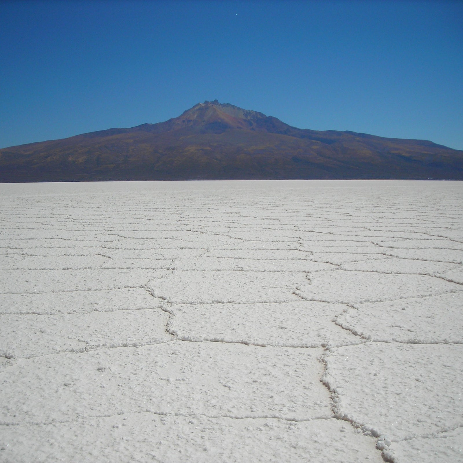 The vast expanse of the Uyuni Salt Flats stretches to the horizon beneath a majestic Andean mountain.