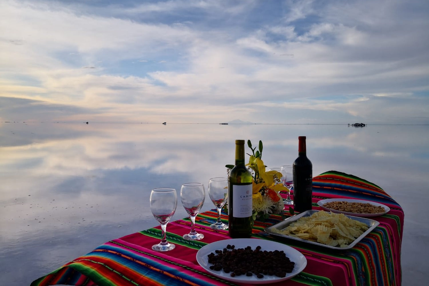 Exclusive dining experience in the middle of the Uyuni Salt Flats, where an elegant picnic is enjoyed surrounded by the magical mirror effect and the infinite vastness of the Bolivian Altiplano.