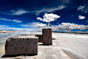 Concrete blocks on a salt flat with a blue sky and clouds in the background