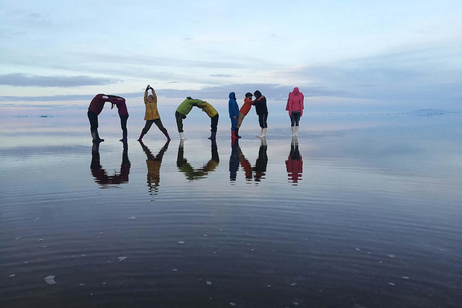 People trick art "Uyuni reflection" at Uyuni salt flat with colorful clothing, Bolivia