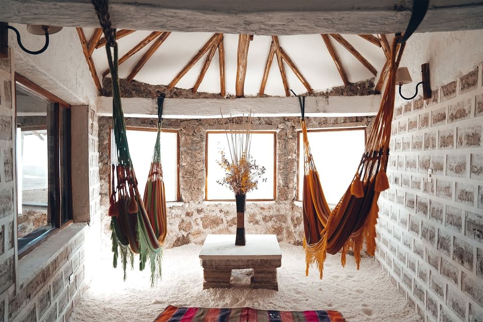 Living room with wooden beams, brick walls, and hanging hammocks.