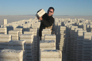 Person holding a block of salt Uyuni salt flat landscape